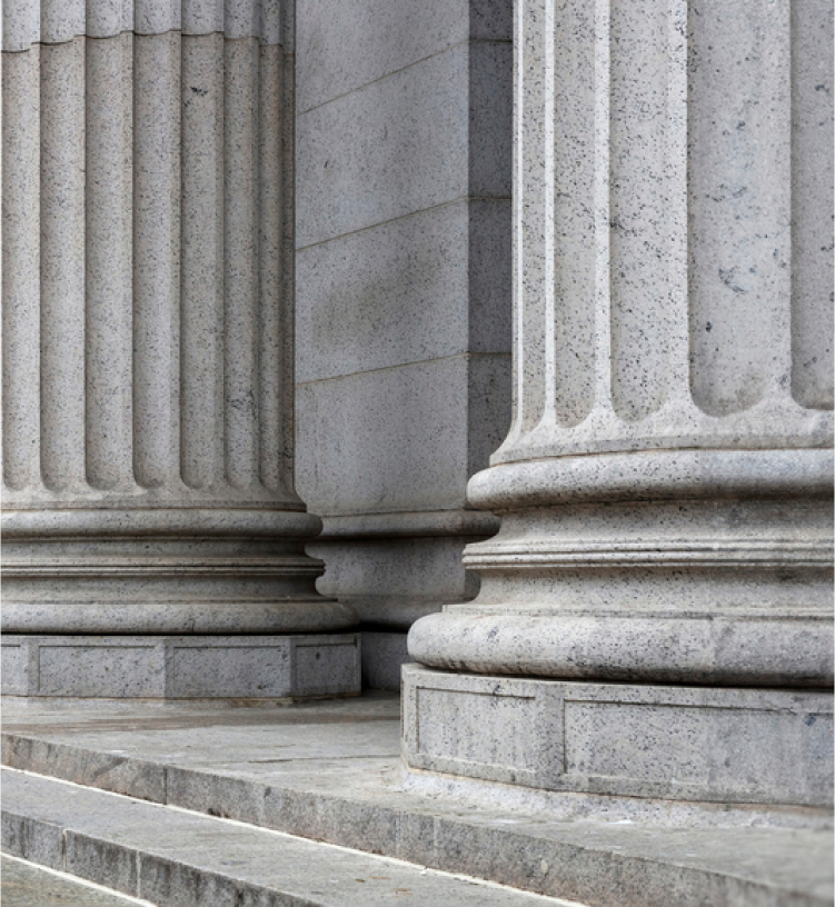 Close-up of gray stone columns with fluted designs and broad bases, positioned on stone steps.