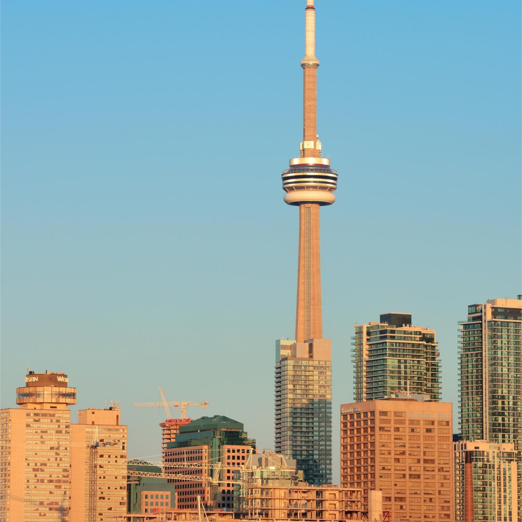 Toronto skyline featuring the CN Tower surrounded by high-rise buildings under a clear blue sky.