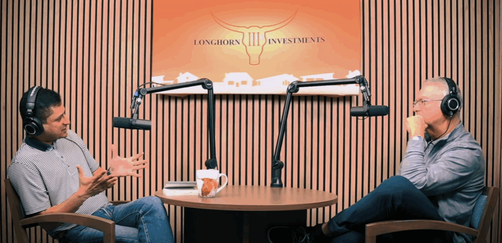 Two men are seated at a round table with microphones in a podcast studio, discussing in front of a Longhorn Investments sign.
